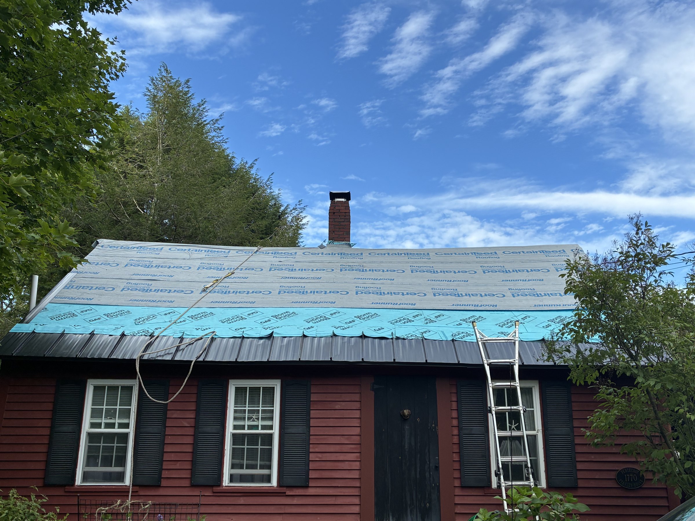 Roof replacement in progress on a red home